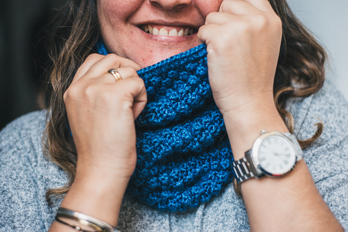Unknown woman with a beautiful smile wearing a hand-knitted blue scarf.