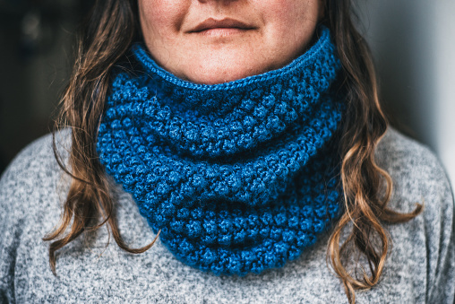 Hand-knitted scarf around the neck of an unknown woman.