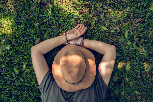Unrecognizable woman on the grass sleeping with a hat over her face. Copy space.