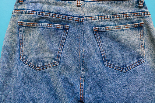 Back pocket of blue denim jeans with prominent stitching. Close up of jeans with lots of pockets