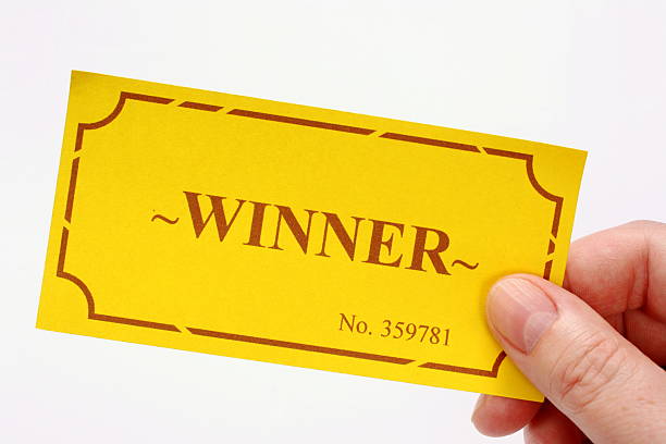 Hand holding out the winning golden ticket for the first prize or other reward in a raffle or lottery.