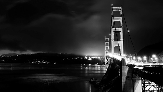 Night time black and white photo of the Golden Gate bridge with fog.