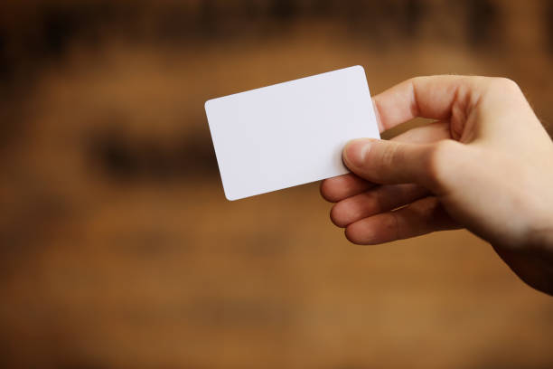istock Male hand holds blank white card mockup on brick wall background. Plain call-card mock up template holding arm. Plastic credit namecard display front. Check offset card design. Business branding. 1790300981