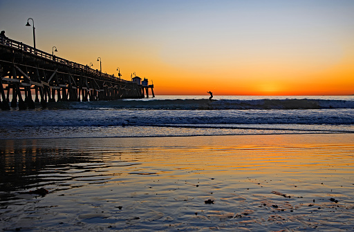 Surfing during sunset at San Clemente, CA pier