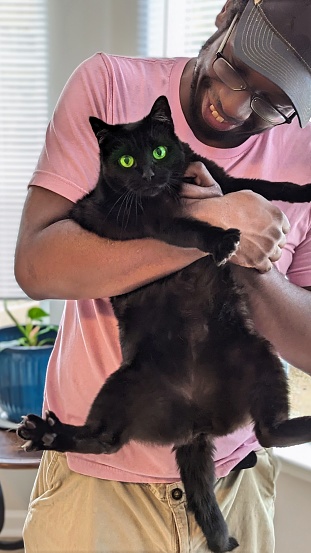 African American Male With His Green Eyes Pet Cat