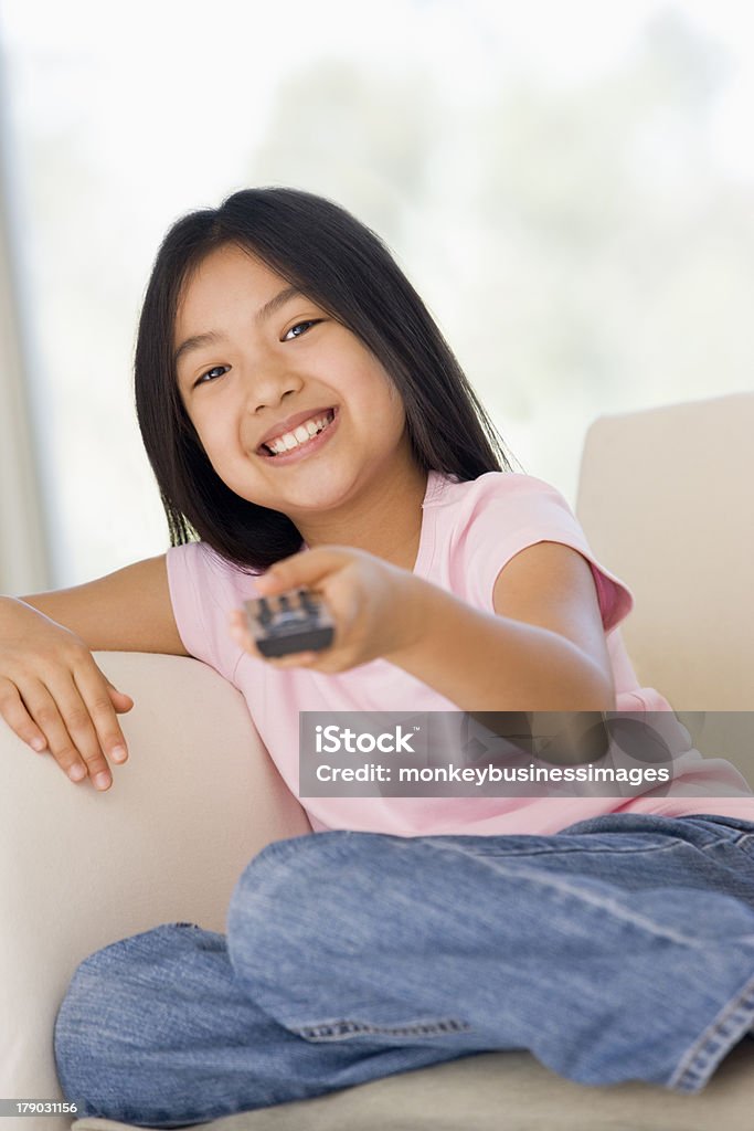 Junges Mädchen im Wohnzimmer mit Fernbedienung lächelnd - Lizenzfrei Fernsehen Stock-Foto