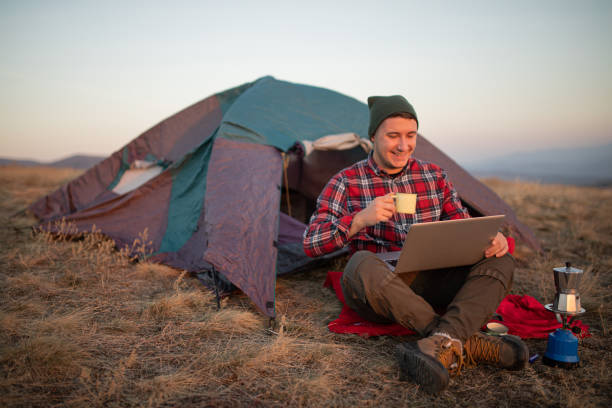 istock Young handsome man having a coffee while working from his camp in a forest stock photo 1790324775