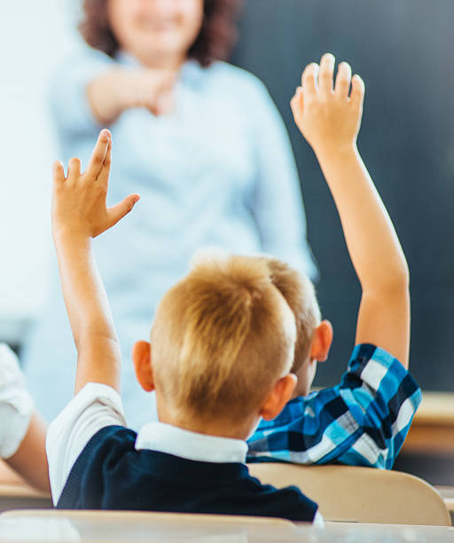 istock School kids raising hands in Classroom 179035881