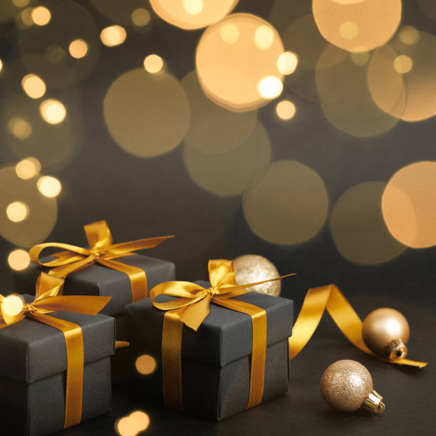 istock Black gift box with golden ribbon bow on black background 1790362696