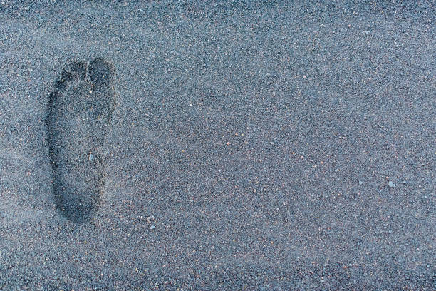 istock A small female left footprint in black volcanic sand with copy space. 1790396650