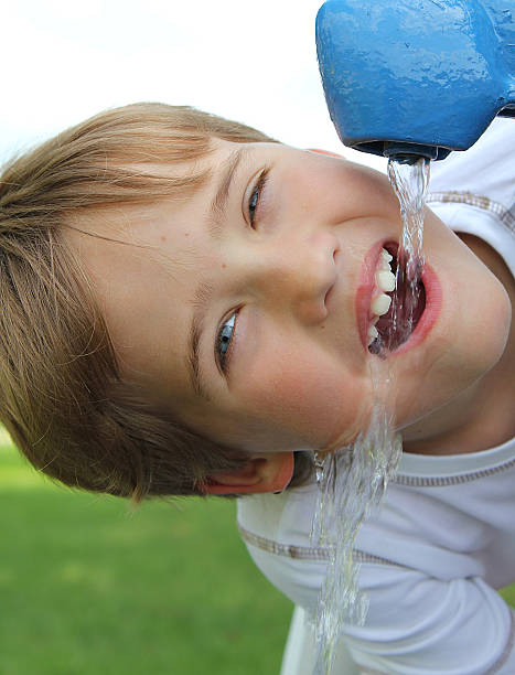 istock Young boy drinking water from a street tap - closeup 179040924