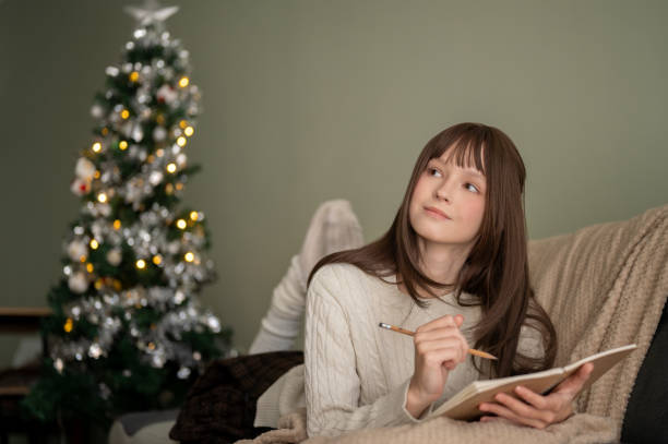 istock A beautiful woman is writing her diary or making a Christmas wish list while lying on a couch. 1790410709