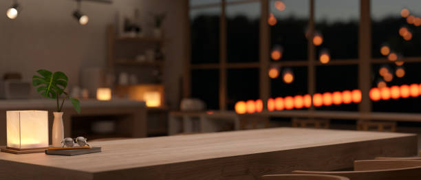 Empty mockup space on a wooden dining table with accessories in a modern dark room at night.