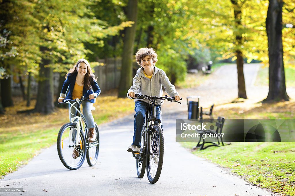 Boy and girl riding bicycles in the city's park Active young people riding bikes  Boys Stock Photo