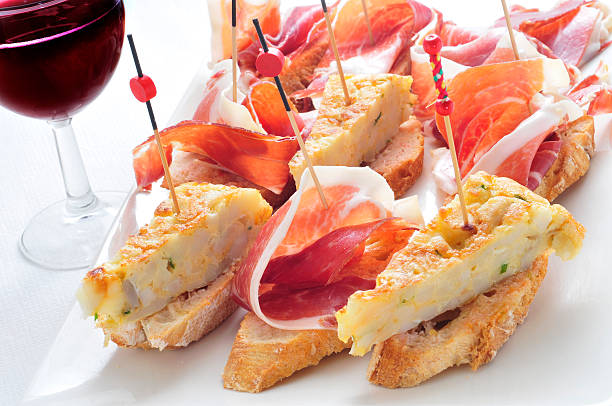 spanish pinchos, tortilla and serrano ham served on bread closeup of a plate with some typical spanish pincho de tortilla and pincho de jamon, spanish omelete and serrano ham served on bread tortilla de patatas stock pictures, royalty-free photos & images