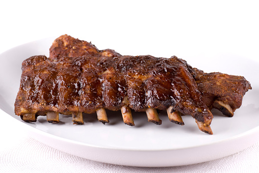 Two glazed rack ribs on a white plate.