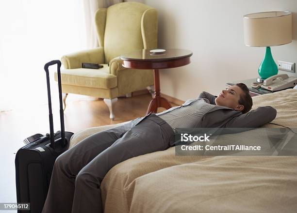 Cansado Mujer De Negocios Que Descansan En Cama En Habitación De Hotel Foto de stock y más banco de imágenes de Adulto