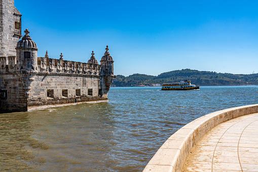 Lisbon, Portugal - Sep 29, 2023: View of Torre de Belém in summer day in the sunshine with tourboat.