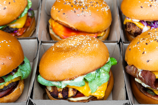 Close-Up perspective of appetising burgers neatly placed within paper boxes.