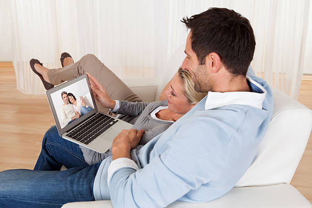 Loving couple having video conference Loving couple having online video conference at home couples online counseling stock pictures, royalty-free photos & images