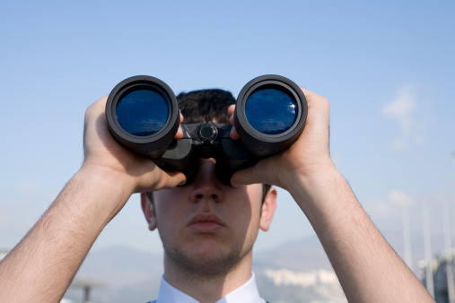 Businessman looking away with binoculars in an office