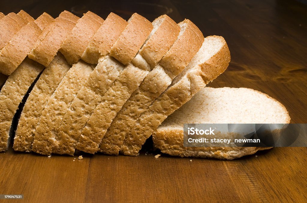 Loaf of Whole Grain Bread Loaf of whole grain bread, sliced on wood table. Sliced Bread Stock Photo