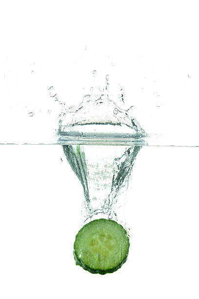 tangy cucumber slice falling vegetables in water, against white background tangy stock pictures, royalty-free photos & images