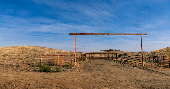 Ranch Entrance with Wooden Fence and Farmhouse on top of a Hill in Rural California