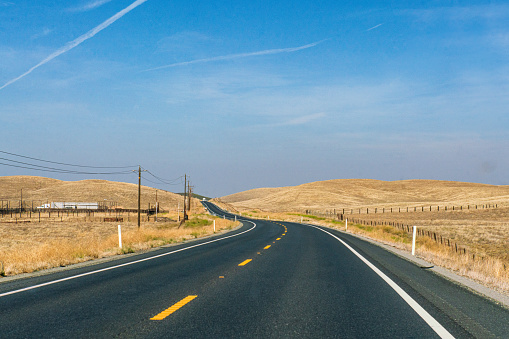 Classic panorama view of an endless straight road running through the barren scenery of the American Southwest with extreme heat haze on a beautiful sunny day with blue sky in summer