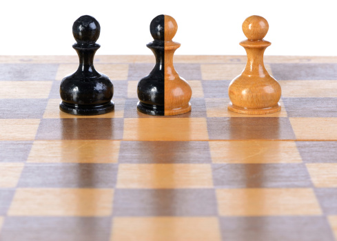 White, black and black-and-white pawns on a chessboard.