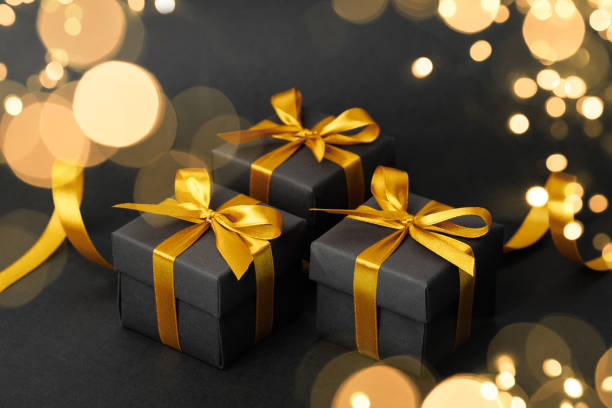 istock Black gift box with golden ribbon bow on black background 1790501155