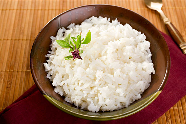 Bowl of freshly prepared jasmine rice Thai fragrant jasmine rice in a bowl, with a garnish of Thai basil which is in flower. More curry here. jasmine rice stock pictures, royalty-free photos & images