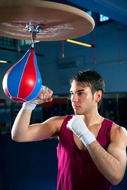 young adult man hitting speed bag in gym. Copy space