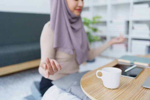 impiegata musulmana medita mentre lavora in ufficio. - yoga business women living room foto e immagini stock