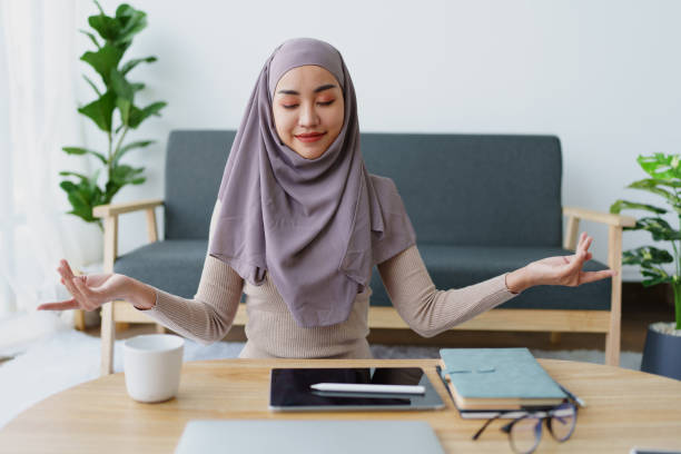 impiegata musulmana medita mentre lavora in ufficio. - yoga business women living room foto e immagini stock