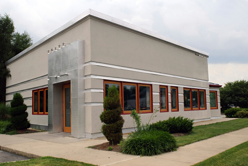 Corner of a small gray business building with overcast day.