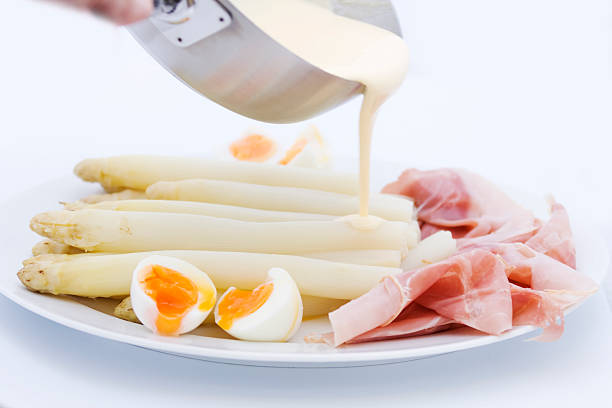 Asparagus spears in Hollandaise sauce on a plate isolated against white