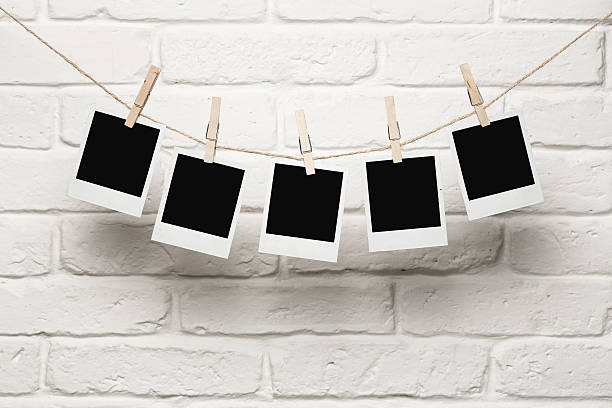 Blank photos hanging on a clothesline Blank photos hanging on a clothesline over brick wall background with copy space surrounding wall photos stock pictures, royalty-free photos & images