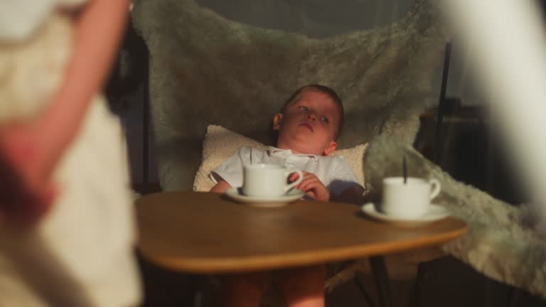 Relaxed child boy lies in fluffy armchair near table