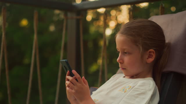 Young girl types messages holding modern smartphone