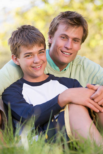 istock Man and young boy sitting outdoors smiling 179056900
