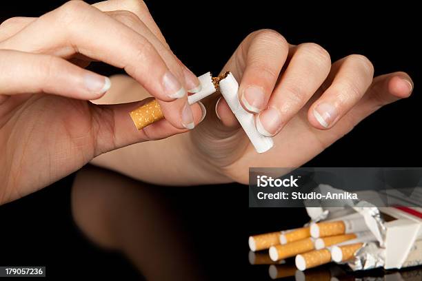 Two Hands Break A Cigarette In Half Next To An Open Packet Stock Photo - Download Image Now