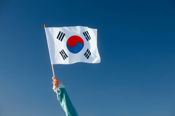 Main agitant un drapeau coréen sur un ciel bleu - Photo