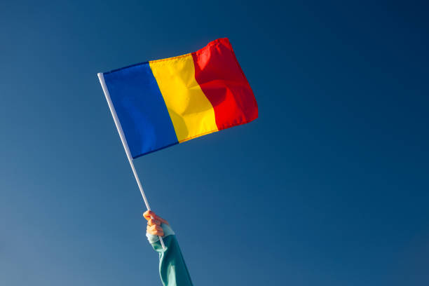 Hand Waiving a Romanian Flag on a Blue Sky