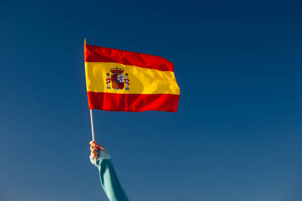 istock Hand Waiving a Spanish Flag on a Blue Sky 1790576416