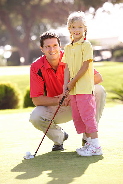 père et sa fille d'enseignement à jouer au golf sur notre putting green - putting down photos et images de collection