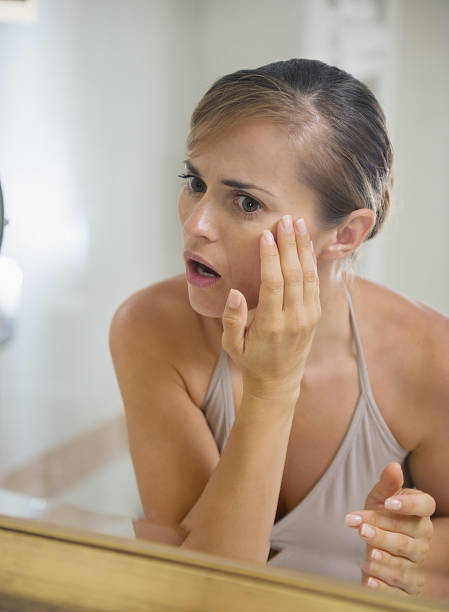 istock Concerned young woman in bathroom checking skin condition 179060305