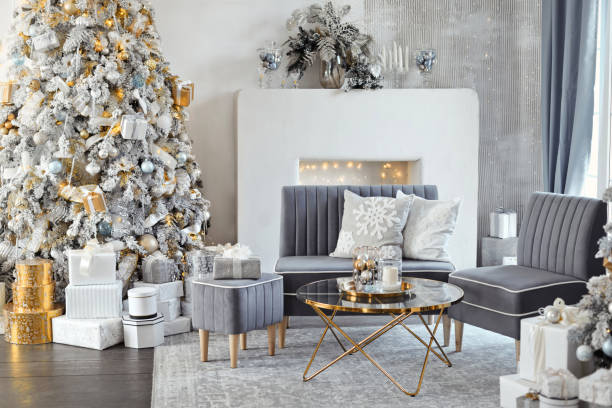 istock Hall room interior with a couch, fireplace with candles and decorated Christmas tree with gifts. Large designer snow tree in lounge with lights and balls in white, gray, gold and silver colors 1790603744