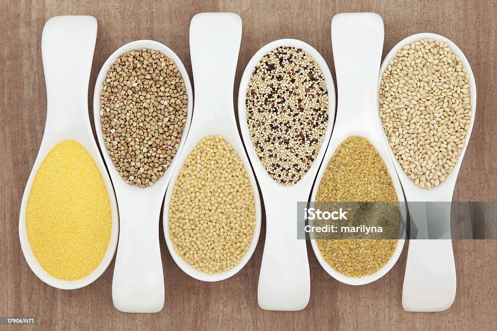 Health Food Healthy grain food selection in white porcelain spoons over papyrus background. Polenta, buckwheat, couscous, quinoa, bulghur wheat and sweet rice, left to right. Couscous Stock Photo