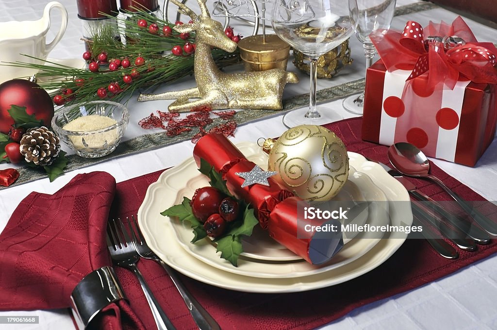 Red theme Christmas dinner table setting Modern and stylish Christmas dinner table setting including plates, glasses and placemats, bon bons and Christmas decorations Landscape (horizontal) composition. Christmas Stock Photo